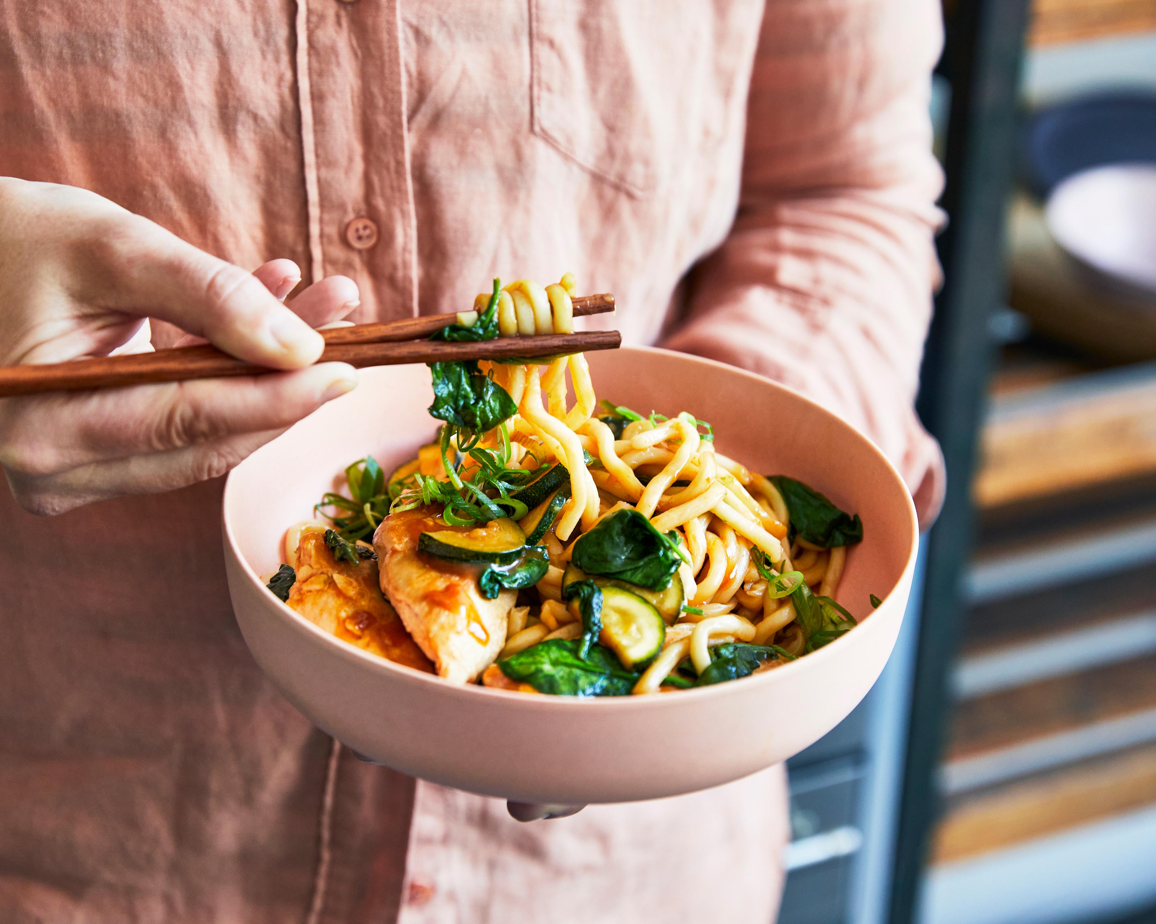 Person holding bowl of noodles
